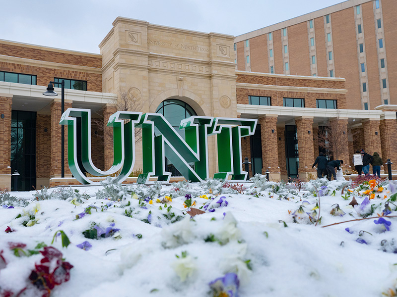 Snow covering flowerbed in front of the UNT Welcome Center